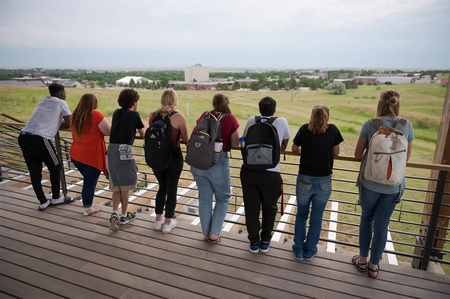 一群学生隔着栏杆望向牧场综合大楼